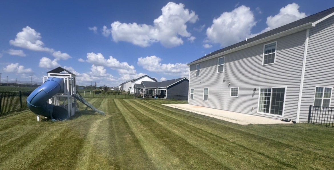 Freshly striped backyard beside a home and playset
